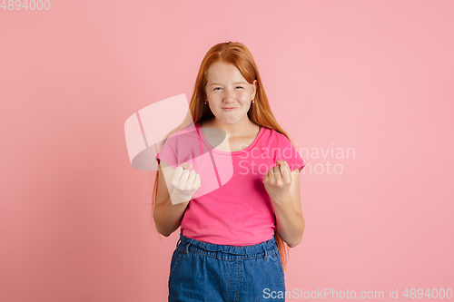 Image of Caucasian teen girl\'s portrait isolated on coral pink studio background.