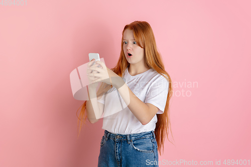 Image of Caucasian teen girl\'s portrait isolated on coral pink studio background.