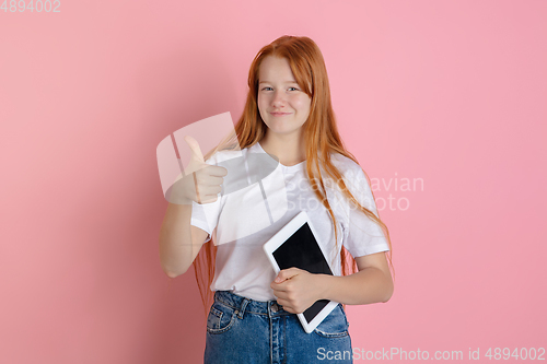 Image of Caucasian teen girl\'s portrait isolated on coral pink studio background.