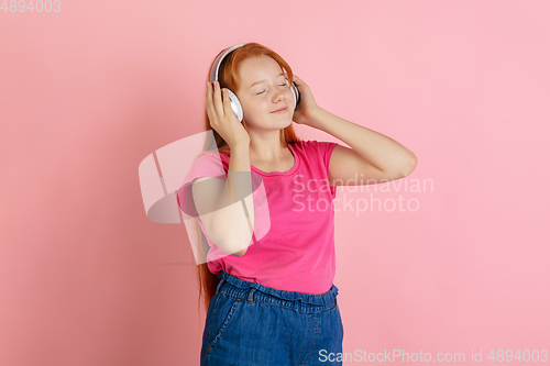 Image of Caucasian teen girl\'s portrait isolated on coral pink studio background.