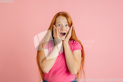 Image of Caucasian teen girl\'s portrait isolated on coral pink studio background.