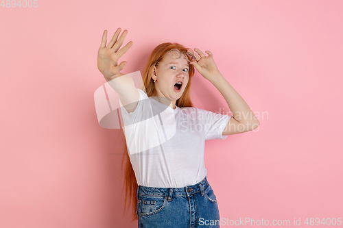 Image of Caucasian teen girl\'s portrait isolated on coral pink studio background.