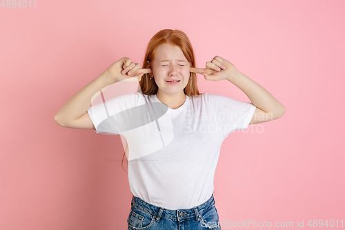 Image of Caucasian teen girl\'s portrait isolated on coral pink studio background.