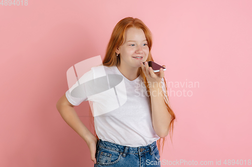 Image of Caucasian teen girl\'s portrait isolated on coral pink studio background.