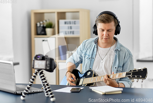 Image of man or blogger with camera playing guitar at home