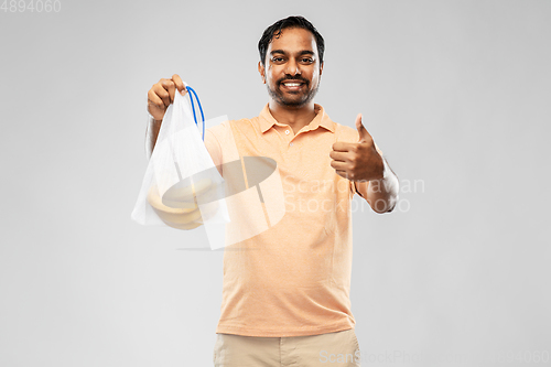 Image of happy man holding reusable string bag with bananas