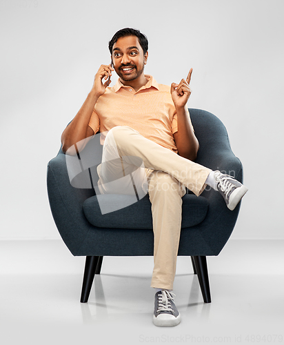 Image of happy indian man calling on smartphone in chair