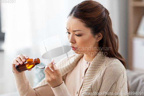 Image of sick asian woman taking medicine at home