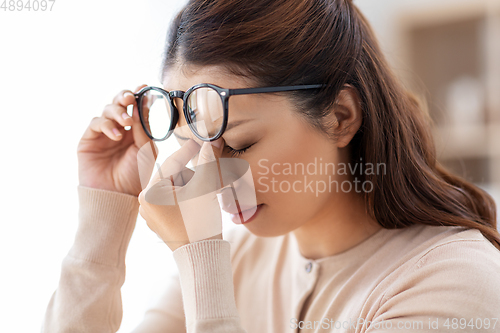 Image of tired woman with glasses rubbing her nose bridge