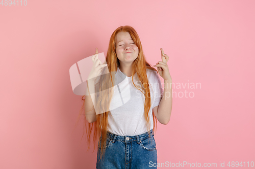 Image of Caucasian teen girl\'s portrait isolated on coral pink studio background.