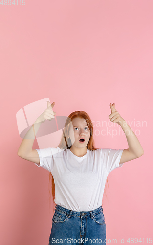 Image of Caucasian teen girl\'s portrait isolated on coral pink studio background.