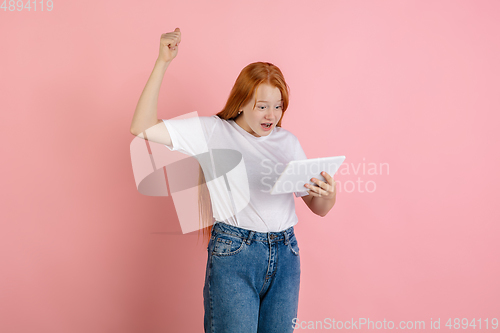 Image of Caucasian teen girl\'s portrait isolated on coral pink studio background.