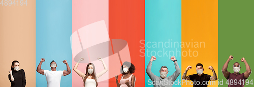 Image of Young attractive people look astonished on multicolored background, wear funny masks