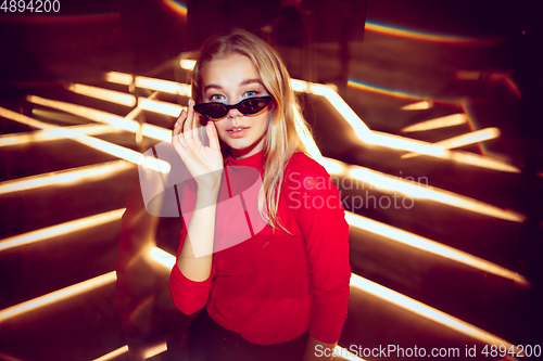 Image of Cinematic portrait of handsome young woman in neon lighted room, stylish musician