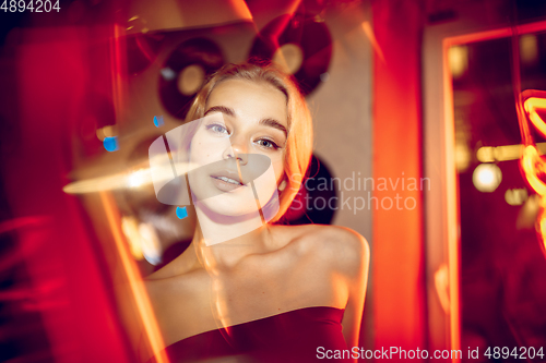 Image of Cinematic portrait of handsome young woman in neon lighted room, stylish musician