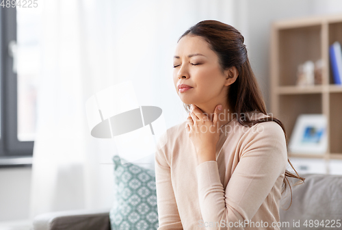 Image of sick asian woman with sore throat at home