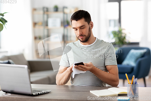 Image of man cleaning phone with wet wipe at home office