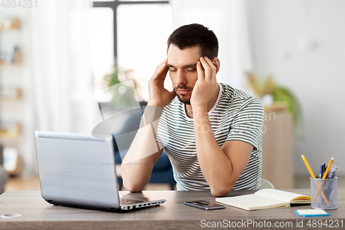 Image of stressed man with laptop working at home office