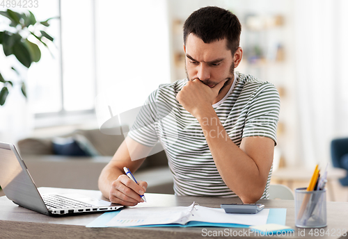 Image of man with files and calculator works at home office