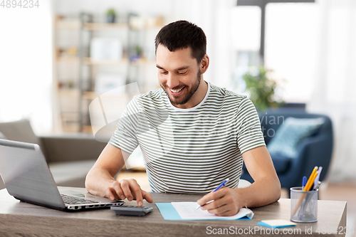 Image of man with files and calculator works at home office