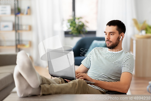 Image of man with laptop and earphones at home