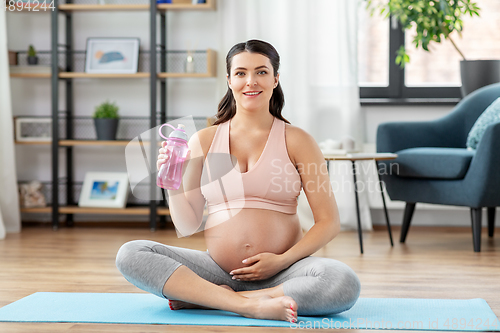 Image of pregnant woman drinking water after yoga at home