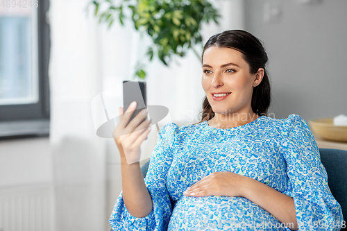 Image of happy pregnant woman with smartphone at home