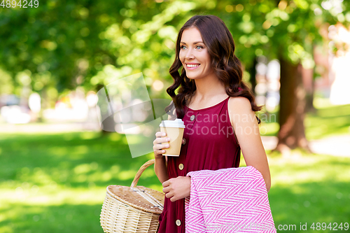 Image of happy woman with picnic basket and coffee at park