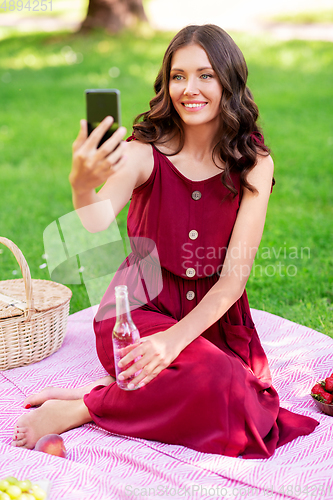 Image of happy woman with smartphone taking selfie at park