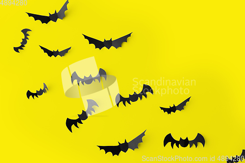 Image of flock of black paper bats over yellow background