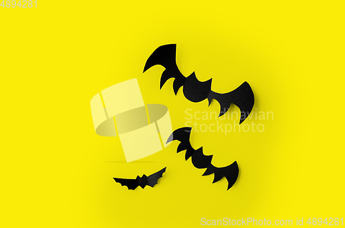 Image of flock of black paper bats over yellow background