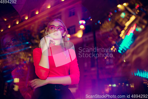 Image of Cinematic portrait of handsome young woman in neon lighted room, stylish musician