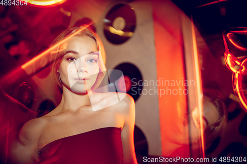Image of Cinematic portrait of handsome young woman in neon lighted room, stylish musician