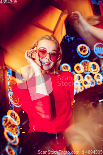 Image of Cinematic portrait of handsome young woman in neon lighted room, stylish musician