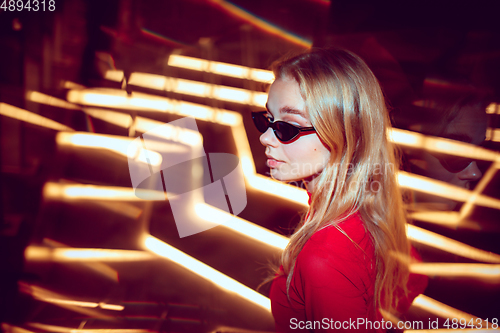 Image of Cinematic portrait of handsome young woman in neon lighted room, stylish musician