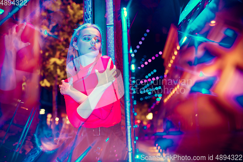 Image of Cinematic portrait of handsome young woman in neon lighted room, stylish musician