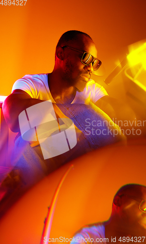 Image of Cinematic portrait of handsome young man in neon lighted room, stylish musician