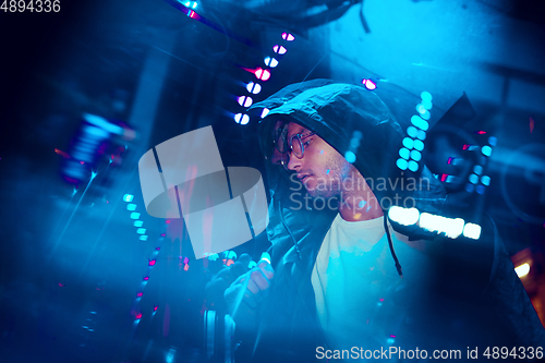 Image of Cinematic portrait of handsome young man in neon lighted room, stylish musician