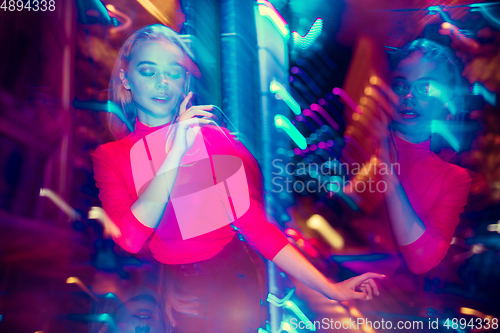 Image of Cinematic portrait of handsome young woman in neon lighted room, stylish musician