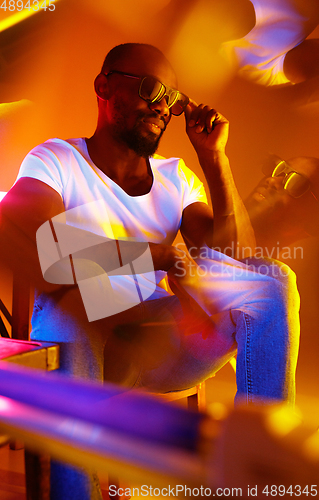 Image of Cinematic portrait of handsome young man in neon lighted room, stylish musician