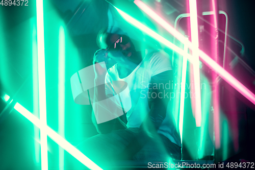 Image of Cinematic portrait of handsome young man in neon lighted room, stylish musician