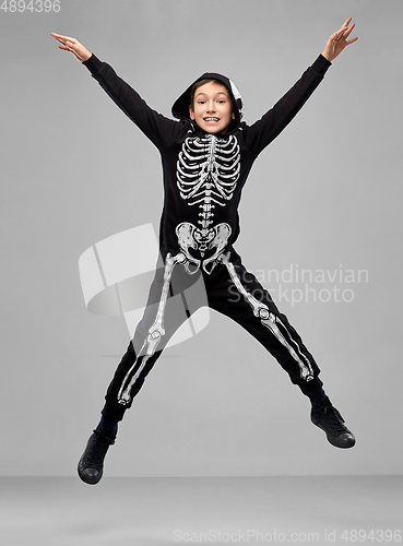 Image of happy boy in halloween costume of skeleton jumping