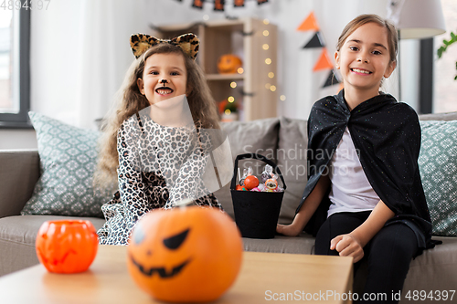 Image of girls in halloween costumes with candies at home