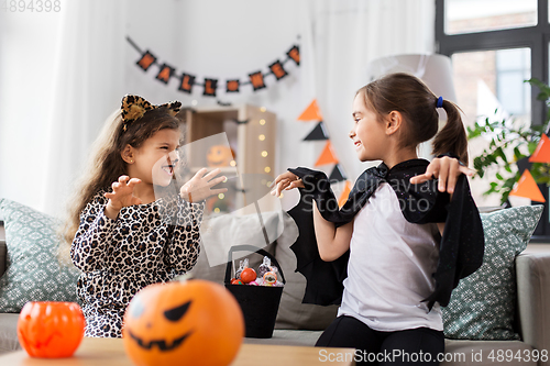 Image of girls in halloween costumes with candies at home