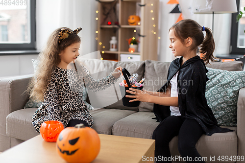 Image of girls in halloween costumes with candies at home