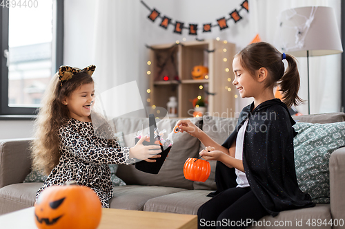 Image of girls in halloween costumes with candies at home