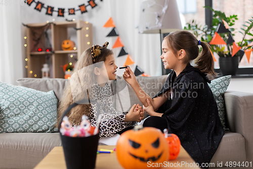 Image of girls doing face painting on halloween at home