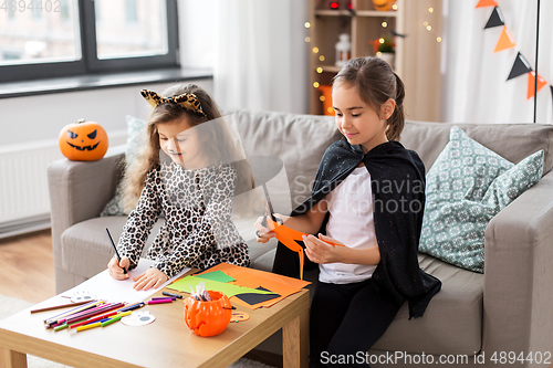 Image of girls in halloween costumes doing crafts at home