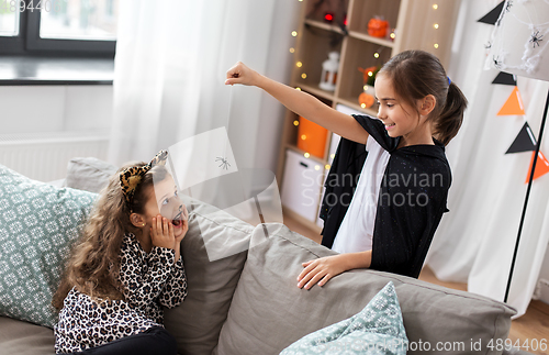 Image of girls in halloween costumes playing with spider