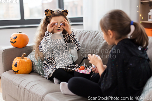 Image of girls in halloween costumes with candies at home